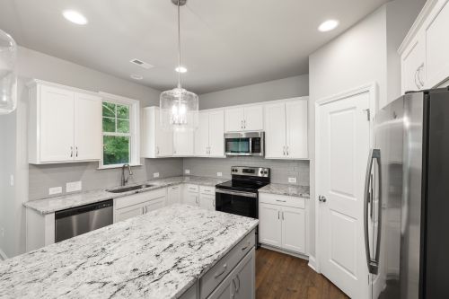 Free Spacious modern kitchen featuring white cabinets, granite countertops, and stainless steel appliances. Stock Photo