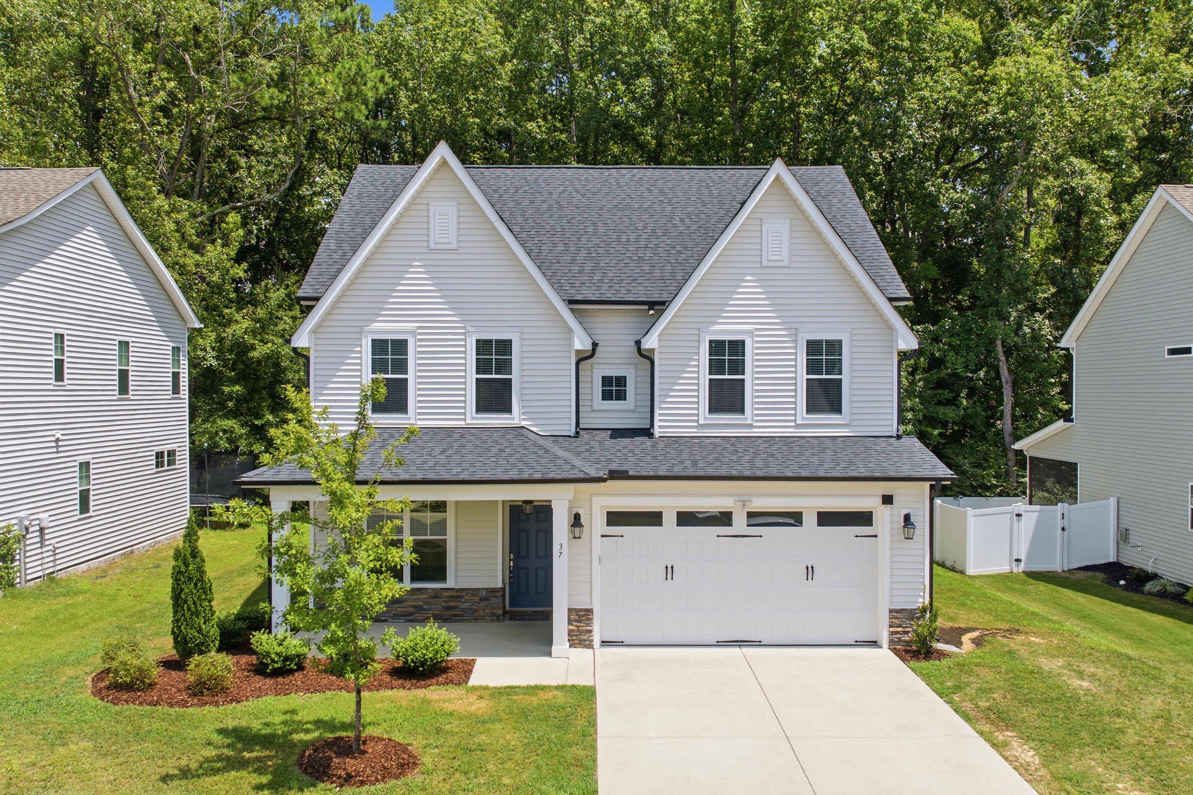 Modern two-story suburban house with a lush green lawn and driveway.