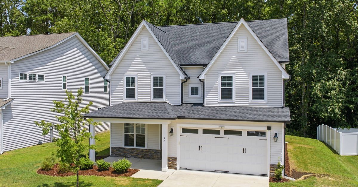 A charming suburban house with a lush garden and detached garage.