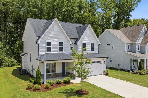 Free Charming two-story suburban house with stylish design and a neat lawn, surrounded by lush trees. Stock Photo