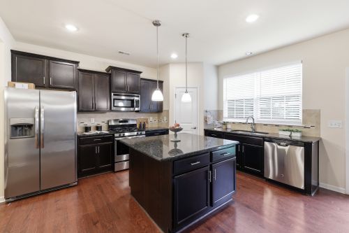Free Spacious kitchen interior featuring dark wood cabinets and modern stainless steel appliances. Stock Photo