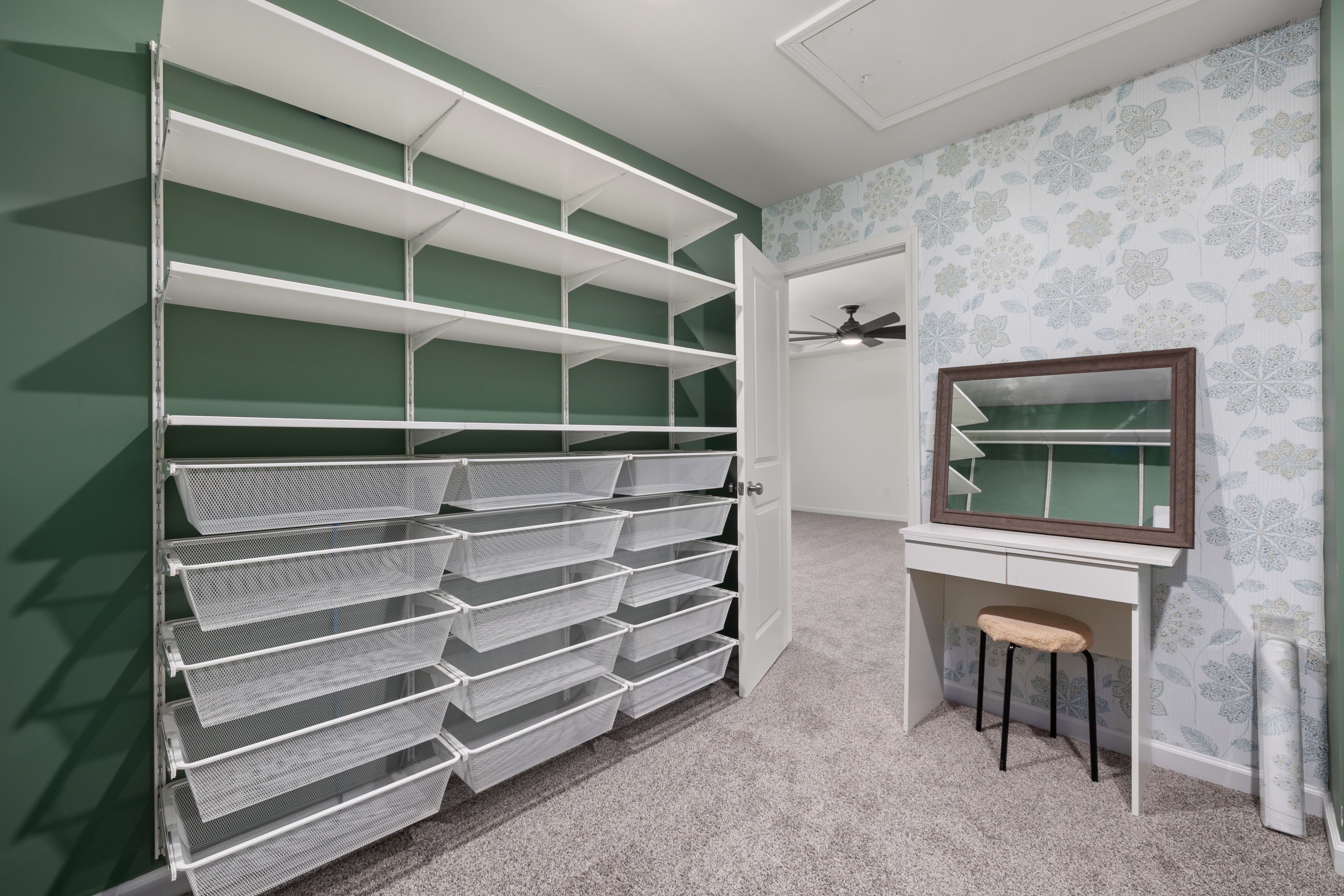 luxury walk in closet with vanity prep station and illuminated mirror