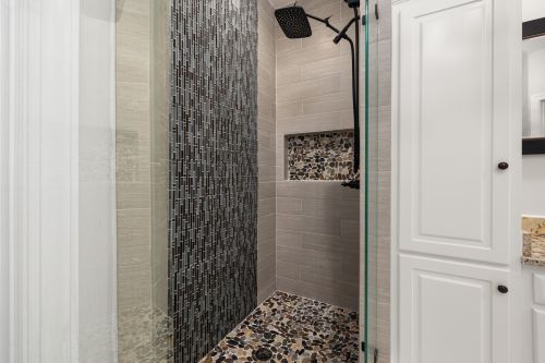 Free Contemporary shower featuring glass doors, mosaic tiles, and stone flooring in a modern bathroom. Stock Photo