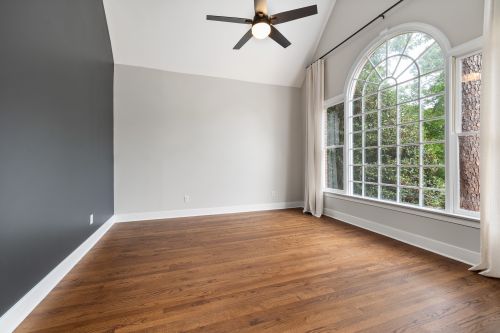 Free Bright empty room with hardwood floors and a large arched window. Stock Photo