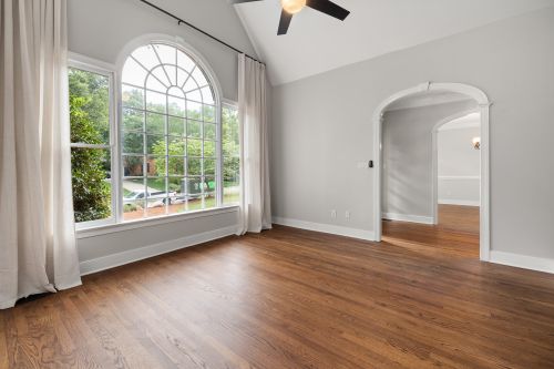 Free Modern empty living room featuring a large arched window and hardwood flooring. Stock Photo