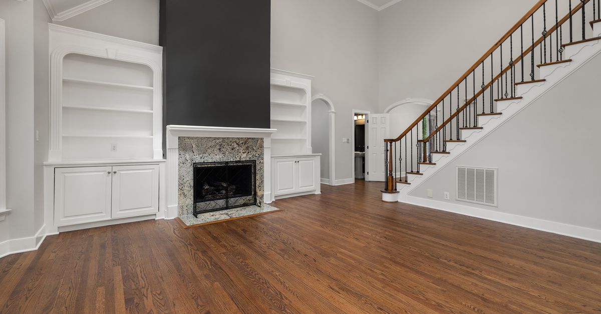 A modern living room featuring hardwood floors, a fireplace, and built-in shelves.