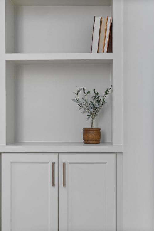 Free Simple white shelf with books and a small potted plant for a modern look. Stock Photo