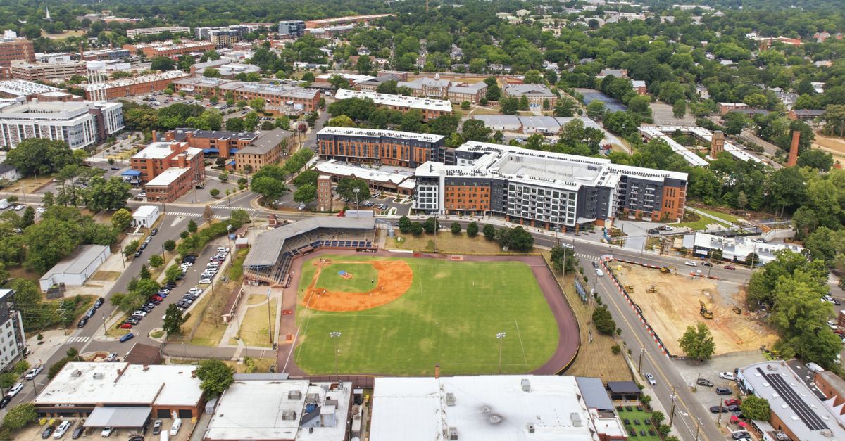 Aerial perspective of baseball field amid modern urban neighborhood.