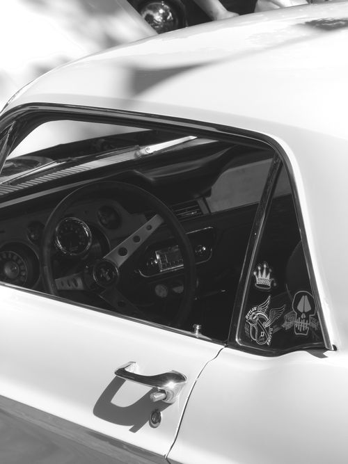 Free Close-up of a classic car interior showing dashboard and stickers in black and white. Stock Photo