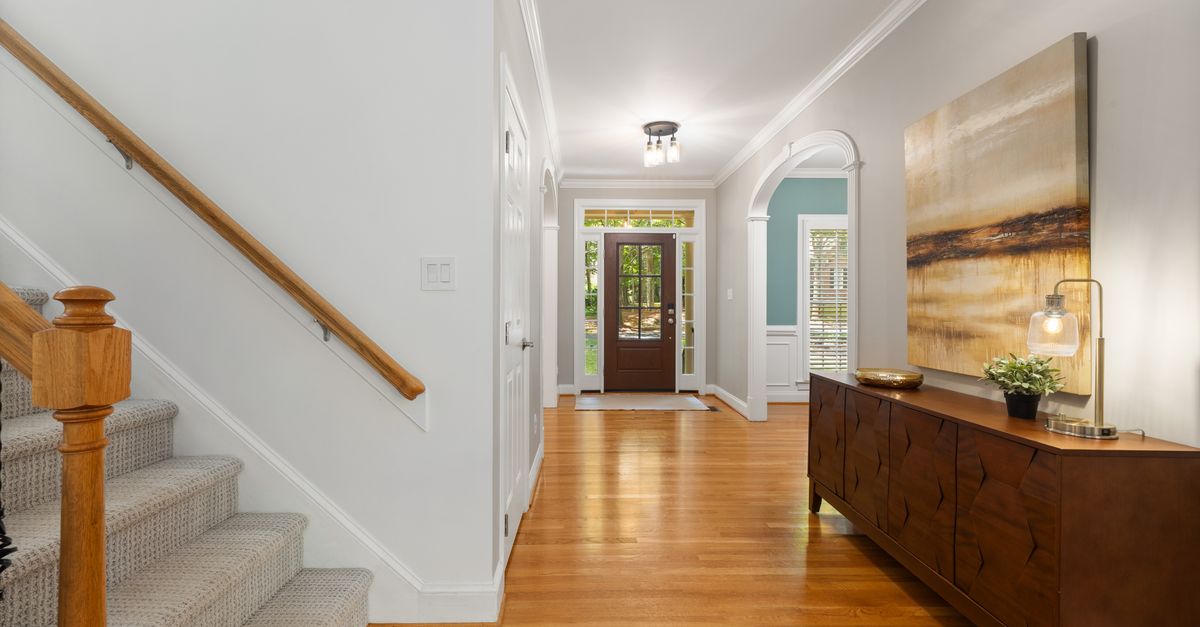 Bright and elegant home entryway showcasing wooden floors and a stylish staircase.