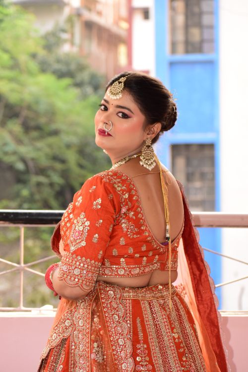 Free Portrait of an Indian woman in traditional orange saree with intricate jewelry. Stock Photo