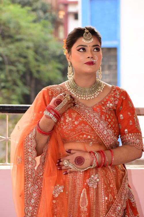 Free Beautiful Indian bride wearing orange saree with intricate jewelry, looking pensive. Stock Photo