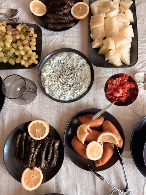 Free An enticing assortment of Turkish meze dishes featuring dolmas, tzatziki, fruits, and pickled vegetables. Stock Photo