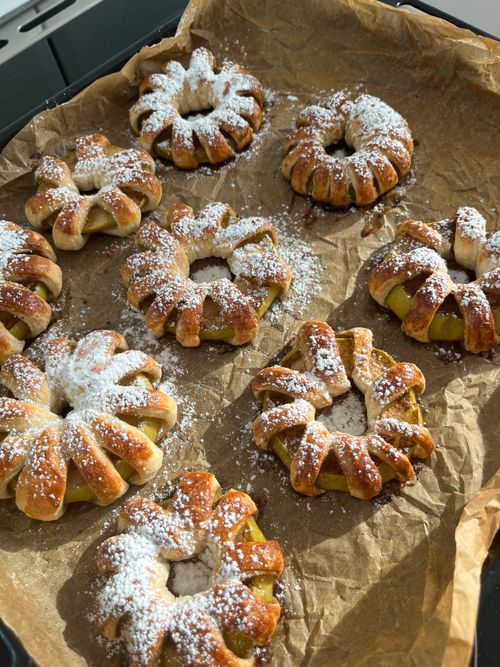 Free Delicious homemade pastries on parchment paper, dusted with powdered sugar, perfect for a cozy treat. Stock Photo