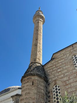 A vibrant day captures the historic minaret against a clear sky in Arnavutköy, Istanbul.