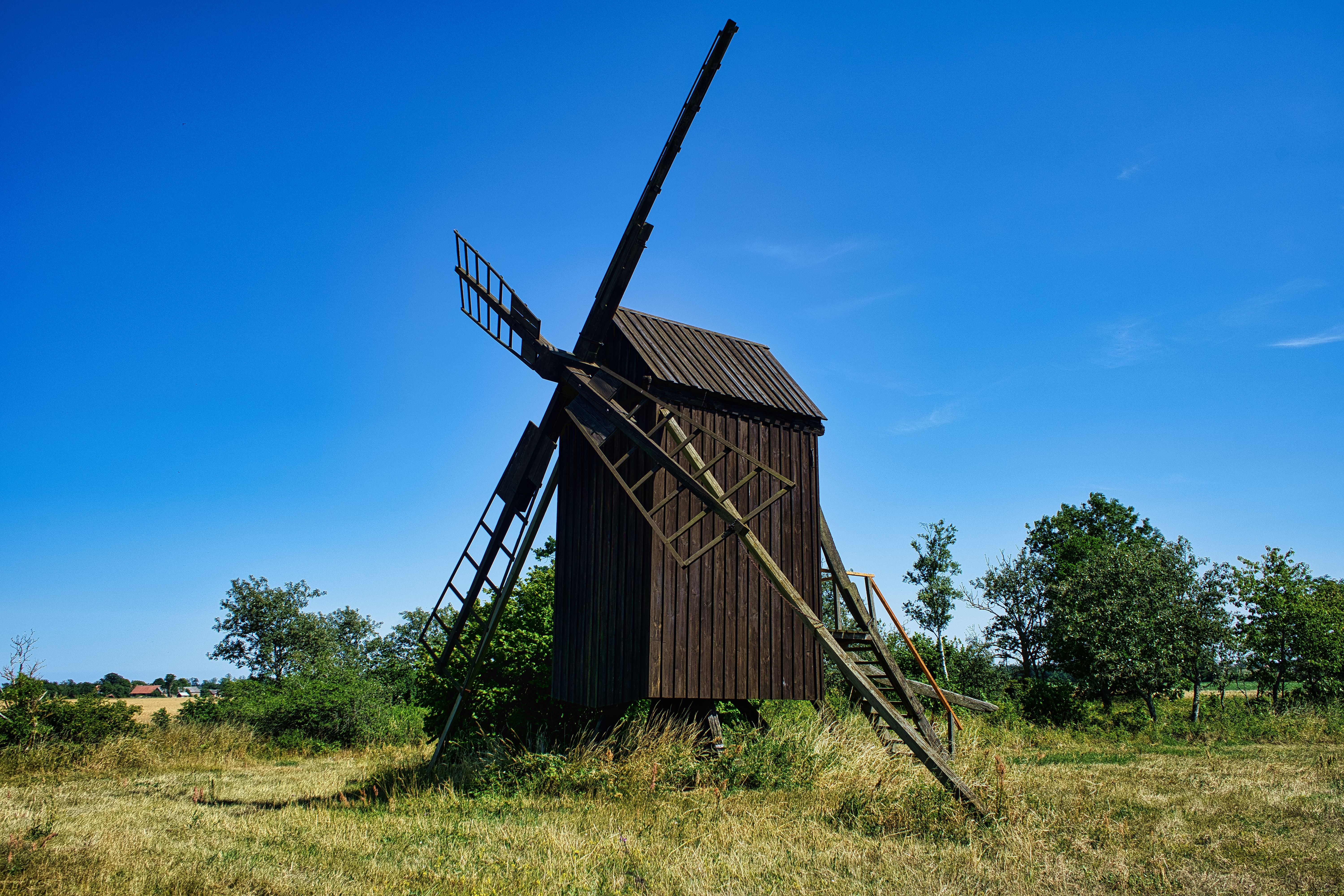 A picturesque traditional windmill under a clear blue sky in Stora Dalby, Sweden.