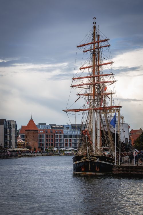 Free Historic tall ship docked in a Baltic harbor with cityscape background. Stock Photo