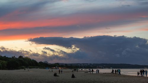Free Serene beach scene at sunset with silhouettes of people enjoying the view. Stock Photo