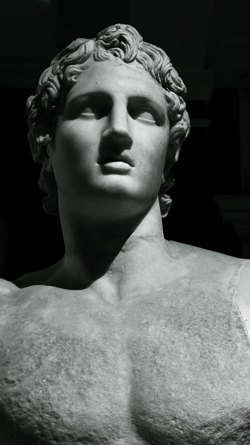 Free Close-up of a classical Greek marble statue head with dramatic lighting, evoking ancient art. Stock Photo