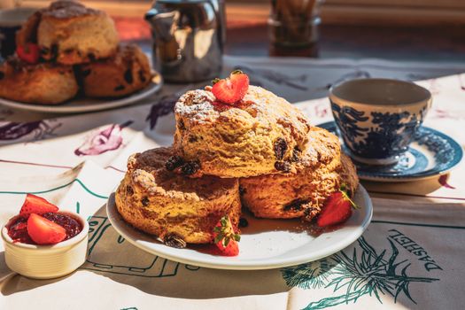 Delicious scones with strawberries and tea setting, capturing traditional English afternoon tea vibe.