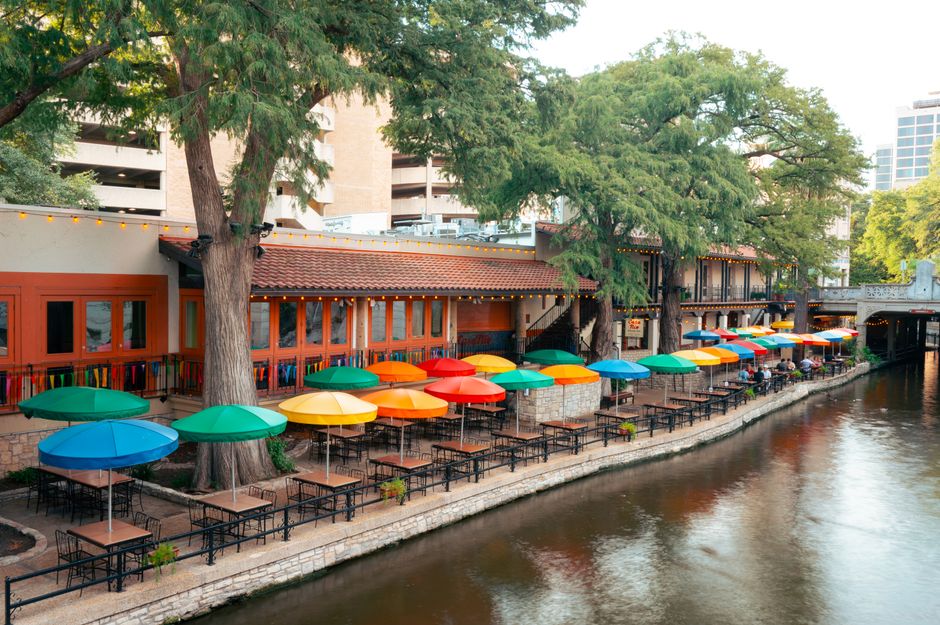 Vibrant umbrellas line the San Antonio Riverwalk, creating a lively outdoor dining scene.