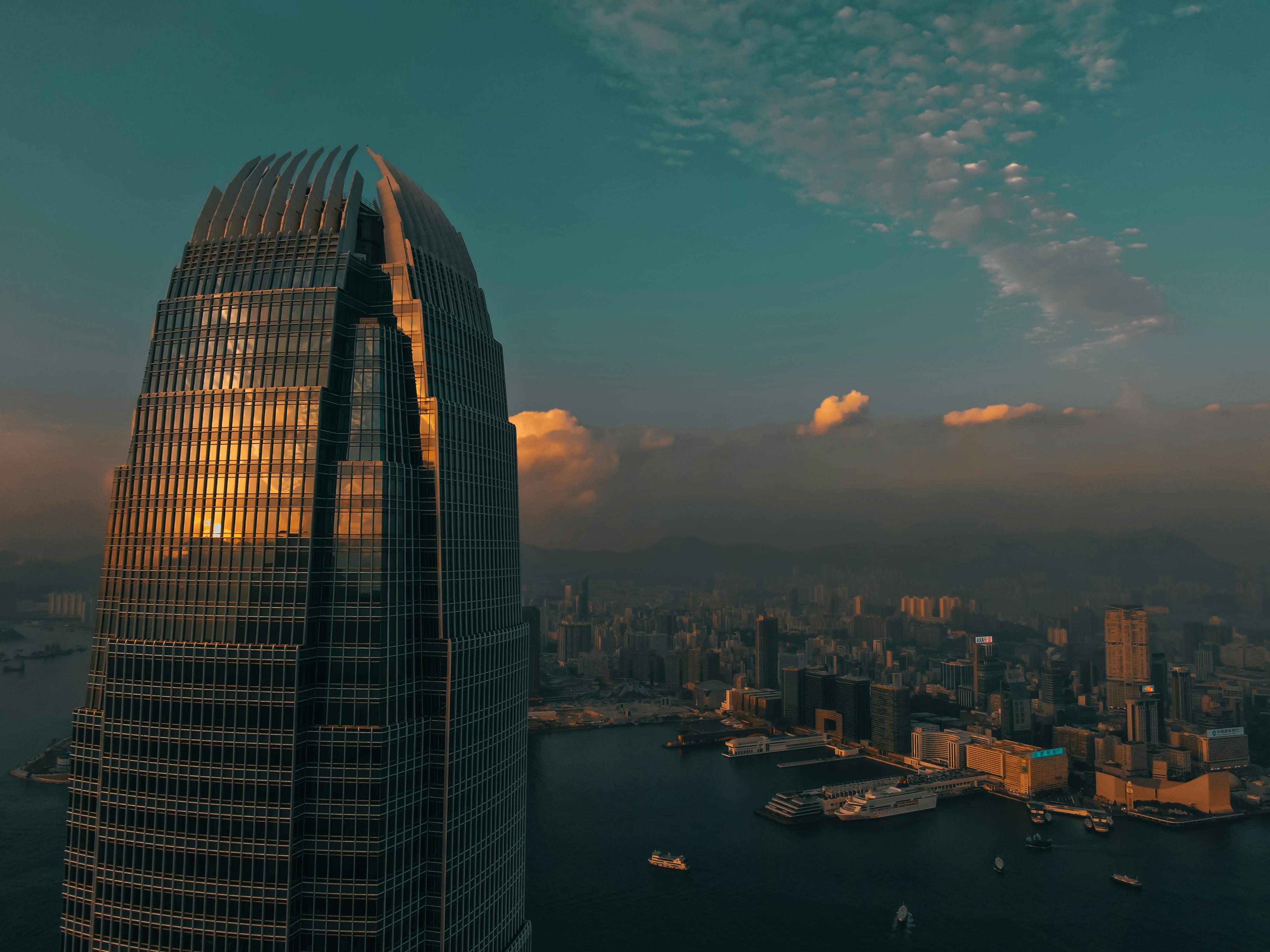 Stunning view of Hong Kong skyline at sunset with a skyscraper reflecting the golden hues.