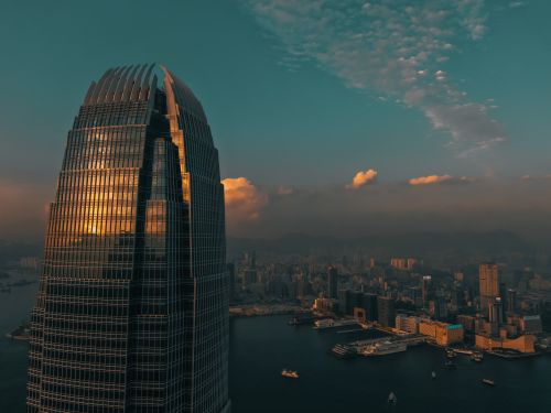 Free Stunning view of Hong Kong skyline at sunset with a skyscraper reflecting the golden hues. Stock Photo