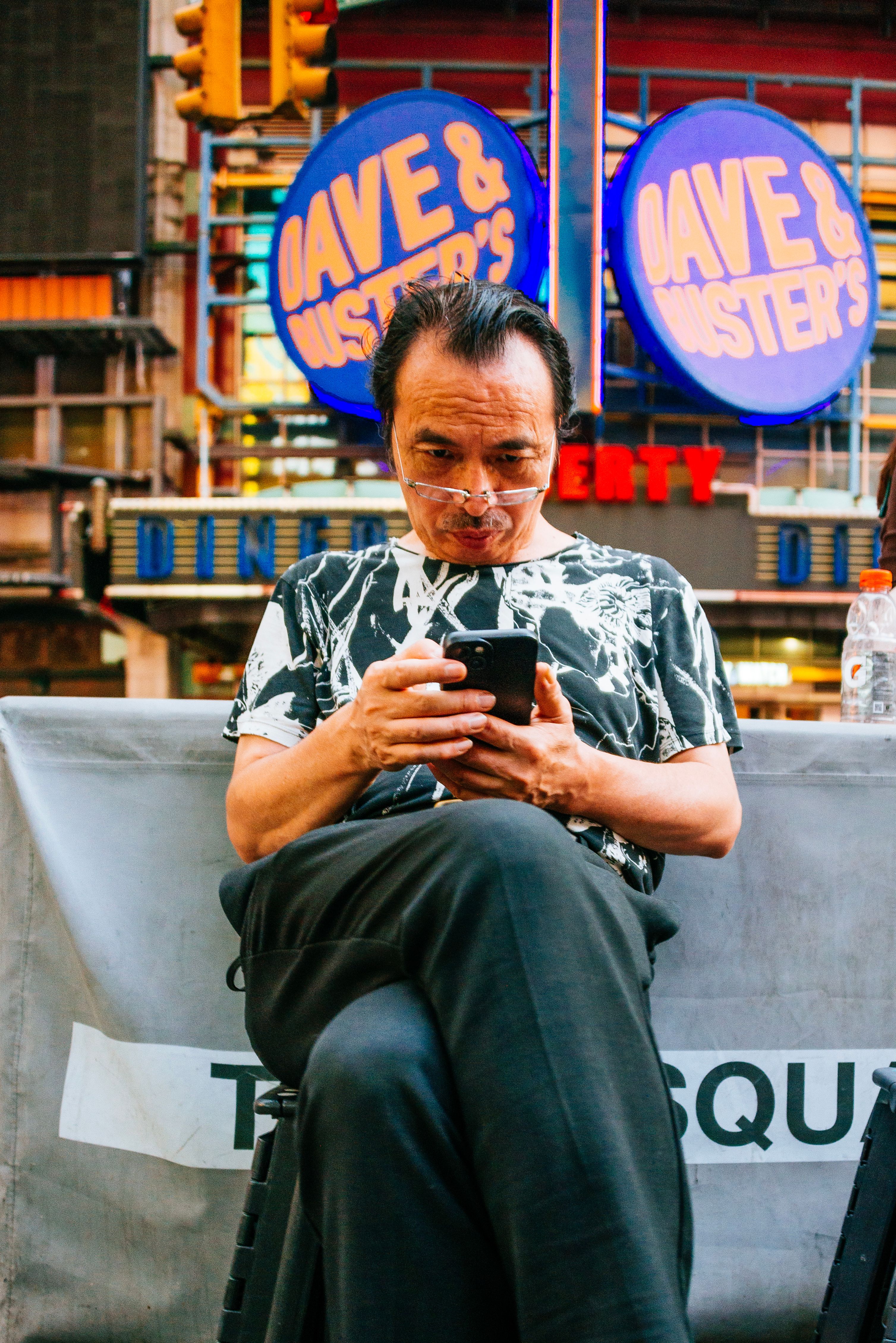 A man engrossed in his smartphone in the bustling environment of Times Square, NYC.