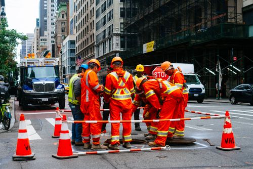 Free Construction workers in safety gear repairing a road in downtown New York City. Stock Photo