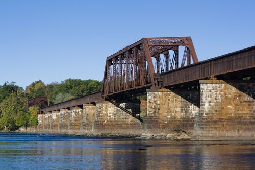 Free A scenic view of a railroad bridge spanning the Connecticut River with autumn foliage. Stock Photo