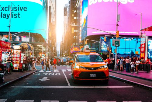 Free Dynamic view of a bustling Times Square with a classic yellow taxi and vibrant billboards in New York City. Stock Photo