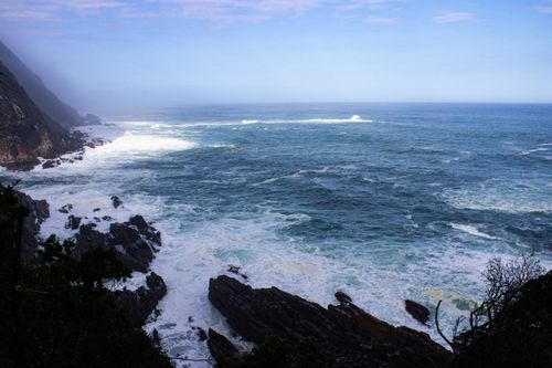 Free Breathtaking view of the ocean waves crashing on a rocky shoreline under a clear blue sky. Stock Photo