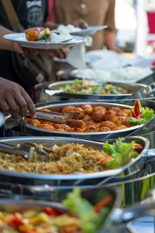 Free A colorful outdoor buffet scene showcasing a variety of delicious dishes served in stainless steel containers. Stock Photo