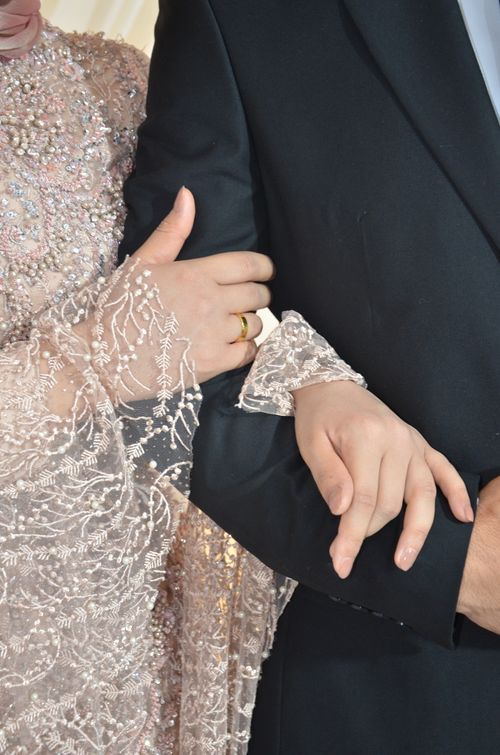 Free Close-up of a well-dressed couple lovingly holding arms, showcasing a wedding theme. Stock Photo