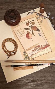 Flat lay of Asian calligraphy set with brushes, incense, and traditional paper art.