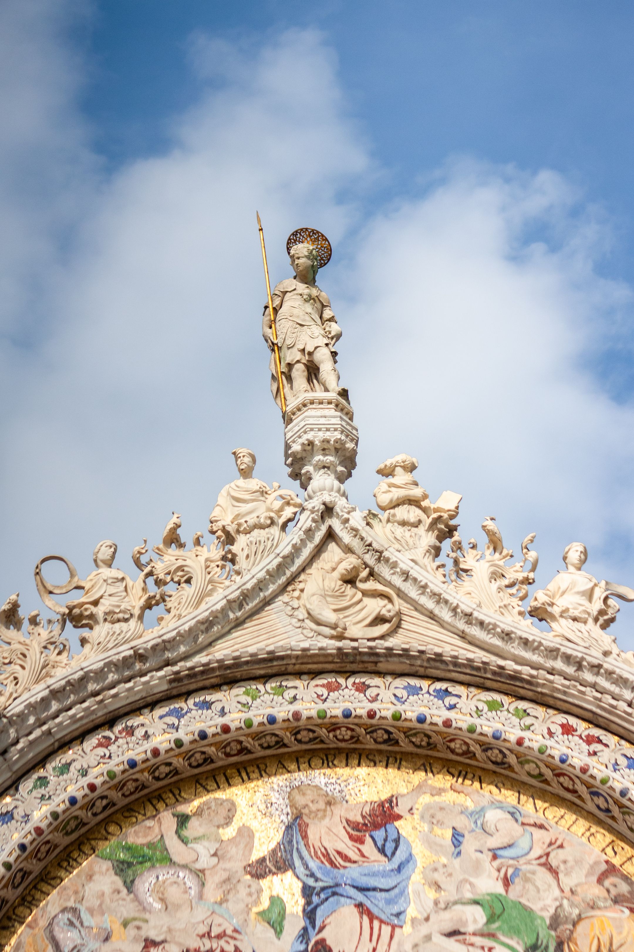 Detailed sculpture on the Basilica San Marco in Venice captured under clear skies.