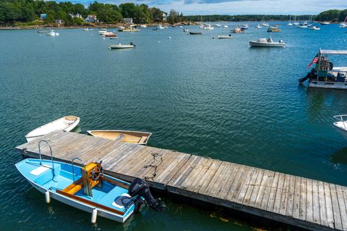 Free Picturesque view of a serene harbor with boats and a wooden dock under a bright sky. Stock Photo