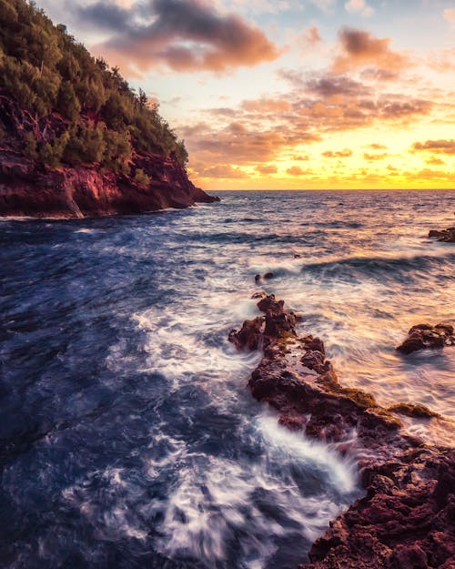 海浪在日落时撞在岩石上