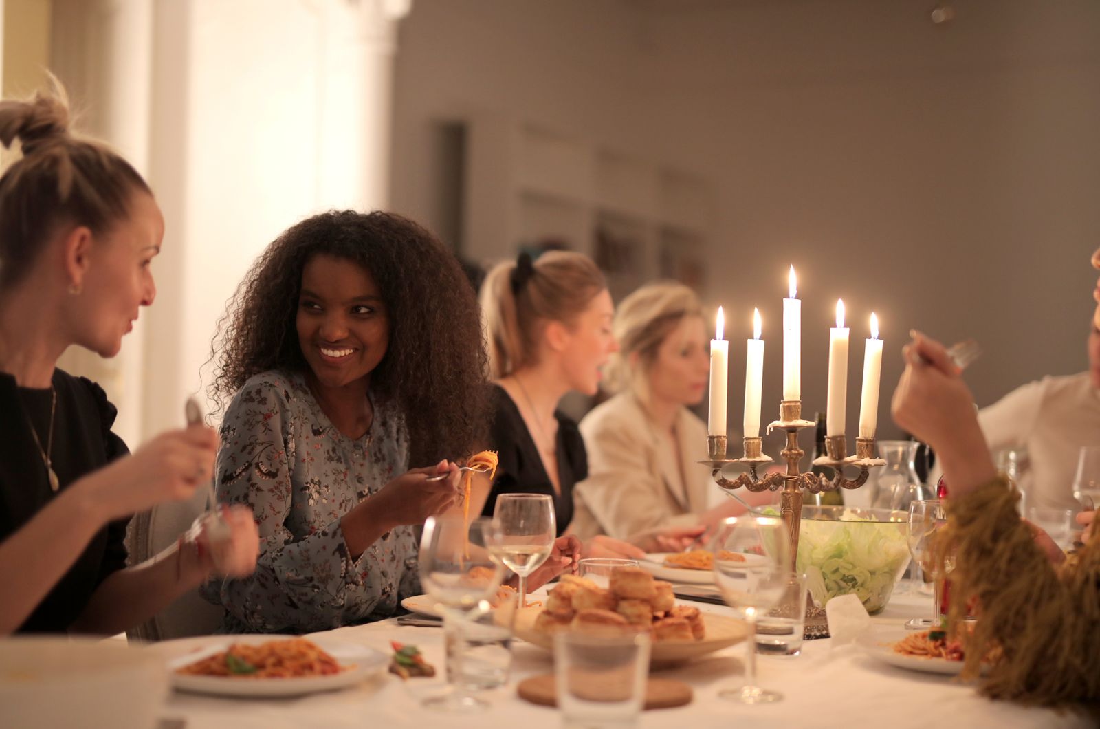 חברים יושבים סביב שולחן מואר בנרות וצוחקים יחד