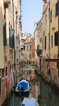 A serene view of a canal in Venice, Italy, showcasing historic architecture and a small boat.