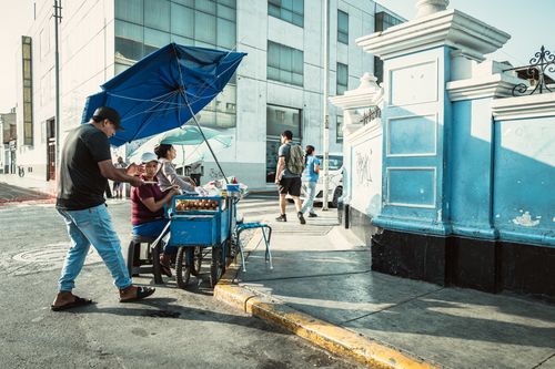 Free Street vendor selling on a sunny day in Trujillo, Peru, with urban buildings in the background. Stock Photo