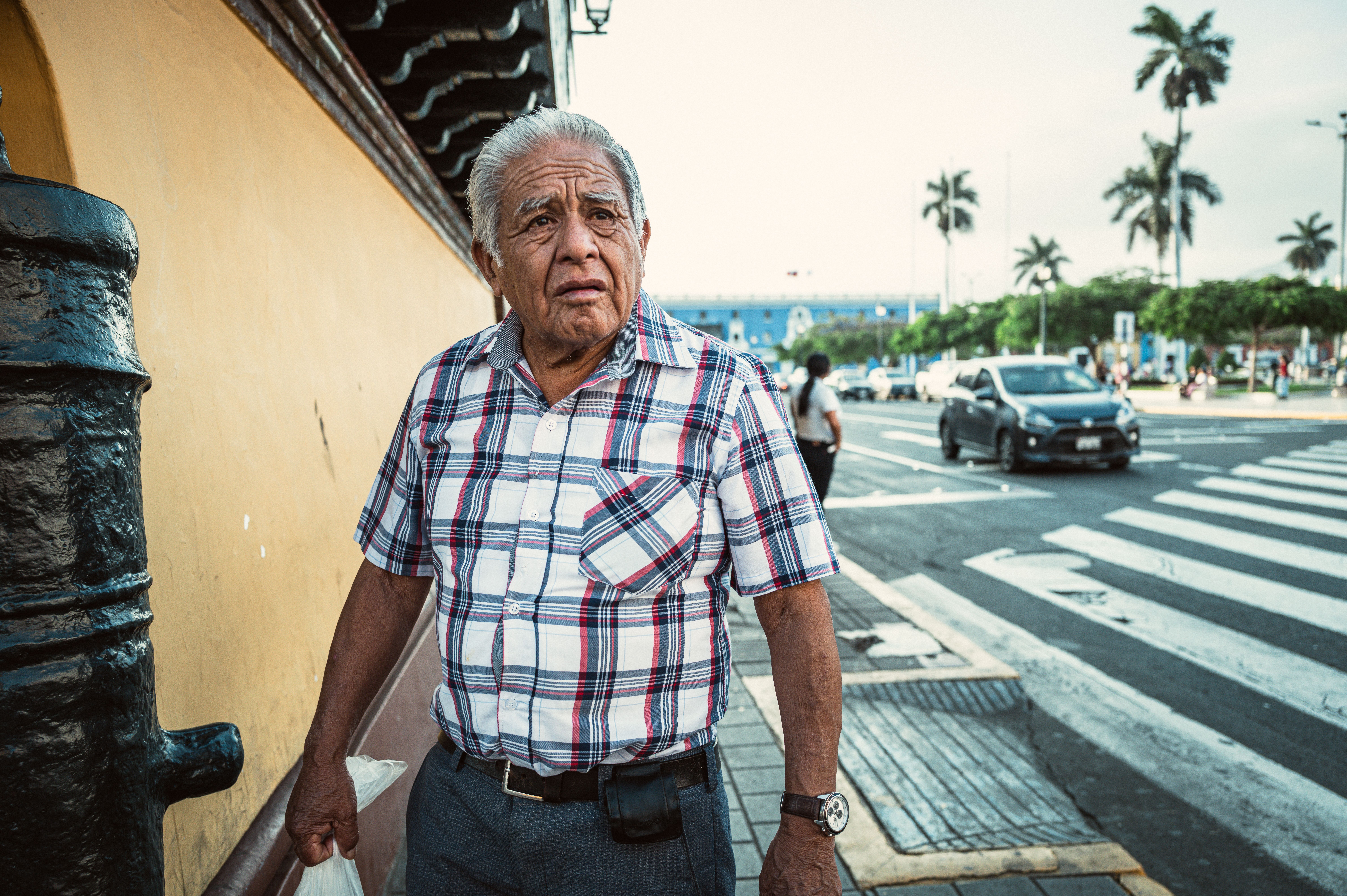 Senior man crossing a vibrant city street in Peru, showcasing everyday life.