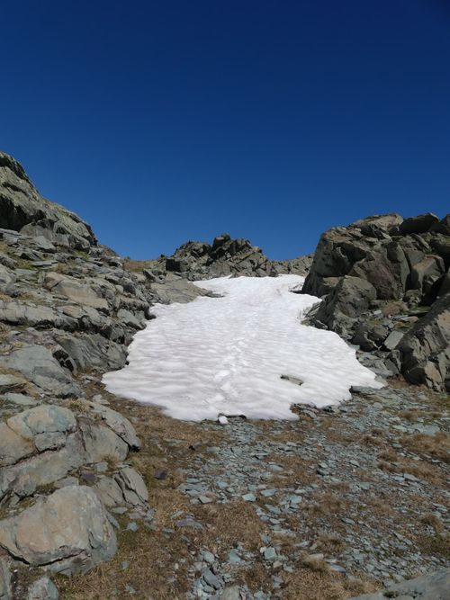 Free Snow-covered rocky pathway in the French Alps under a clear blue sky. Stock Photo