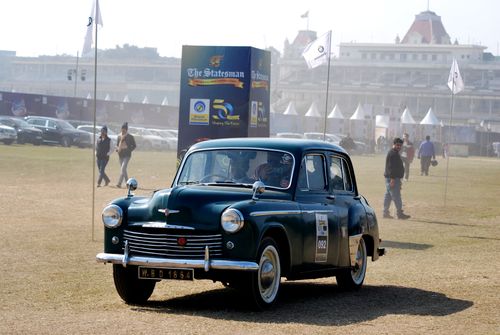 Free Vintage green car showcased at an outdoor auto show with spectators and flags visible. Stock Photo