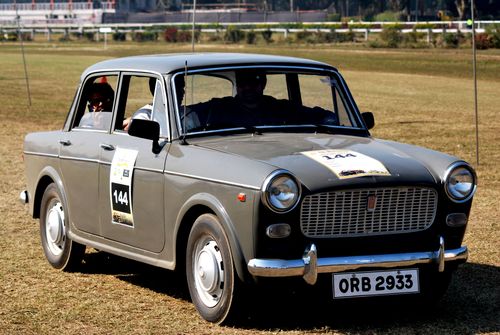 Free A vintage Fiat 1100 participating in an outdoor car rally event on a sunny day. Stock Photo