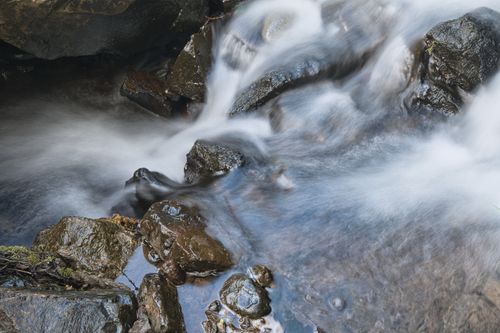 Free Beautiful long exposure shot of a stream flowing over rocks, creating a serene and tranquil natural scene. Stock Photo