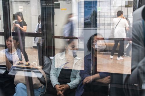 Free Reflection of masked commuters inside a busy urban train station, showcasing daily life. Stock Photo
