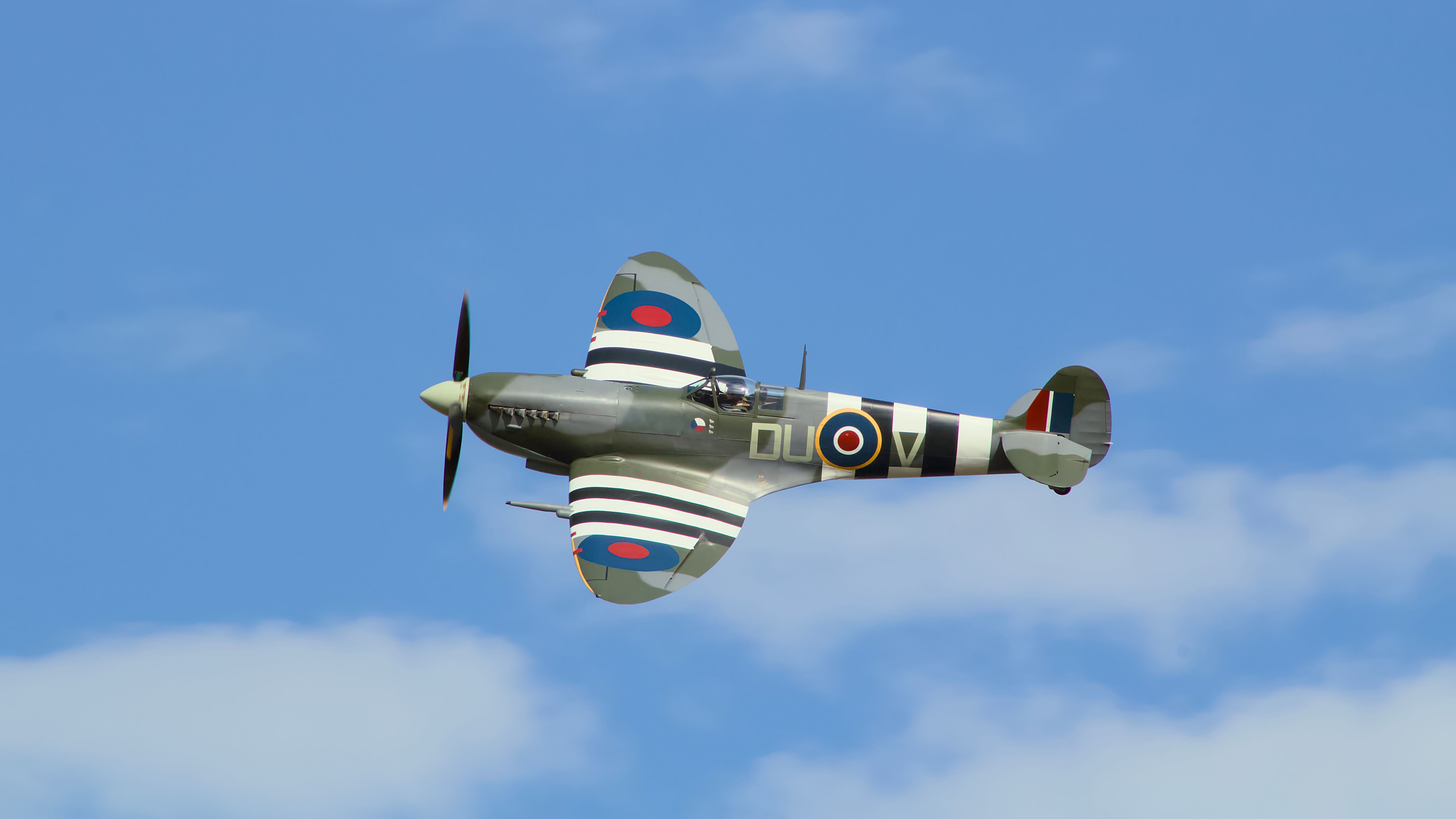 A classic Spitfire warbird gracefully flying against a clear blue sky.
