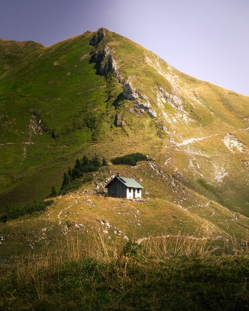 Free A solitary cabin nestled in the scenic Bavarian Alps under a clear sky, perfect for nature lovers. Stock Photo