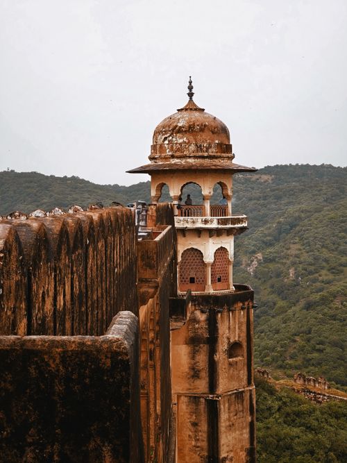 Free A weathered historic tower at an ancient fort amidst scenic hills in Rajasthan, showcasing architectural beauty. Stock Photo